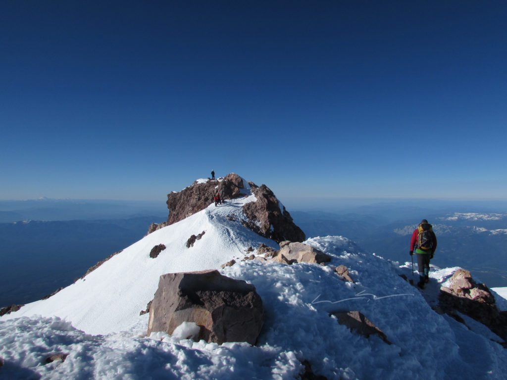 brandon walking down the summit ridge of mount shasta